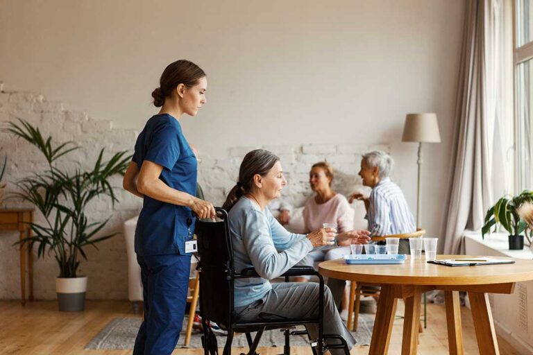 Older adults participating in a gentle group exercise class with a staff member supervising in a well-lit common area.