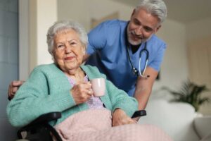 Older adults perform seated and standing exercises with chairs in a bright assisted living activity room.